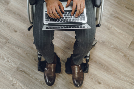 Disabled man in a wheelchair using laptopの写真素材