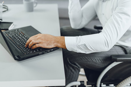 Disabled man in a wheelchair using laptopの写真素材