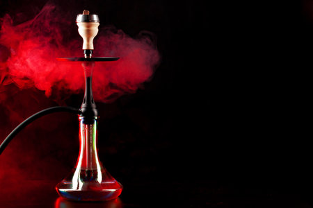 Smoking hookah on black background with color fogの写真素材