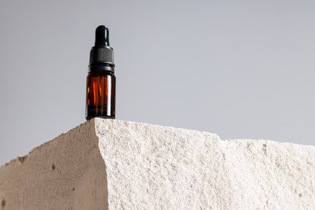 Glass bottle with cosmetic oil on cinder blockの写真素材