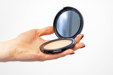 Female hand holding compact powder against gray backgroundの写真素材