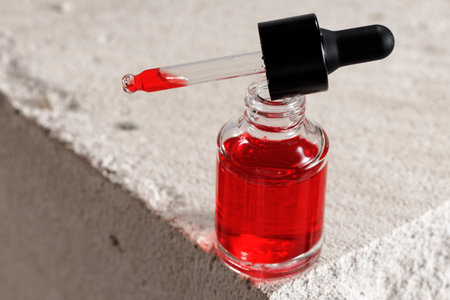 Glass bottle with cosmetic oil on cinder blockの写真素材