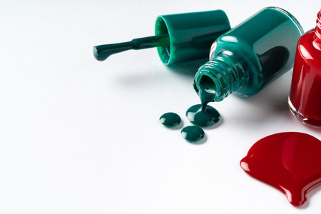 Nail polishes spilled out of bottles on white backgroundの写真素材