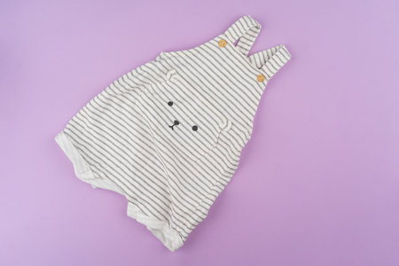 Baby girl clothes on lilac pastel background