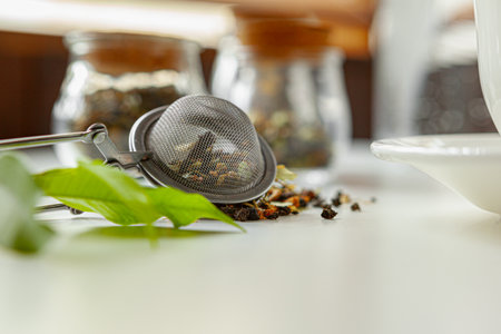 Glass jars with dry tea leaves close up on white table