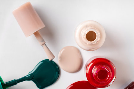 Nail polishes spilled out of bottles on white backgroundの写真素材