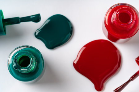 Nail polishes spilled out of bottles on white backgroundの写真素材