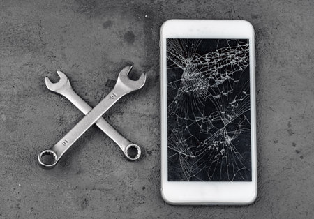 Crashed smartphone with repairing tools on grey backgroundの写真素材