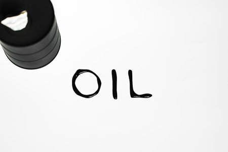 Oil industry concept. Spilled oil from a mini barrel on white backgroundの写真素材