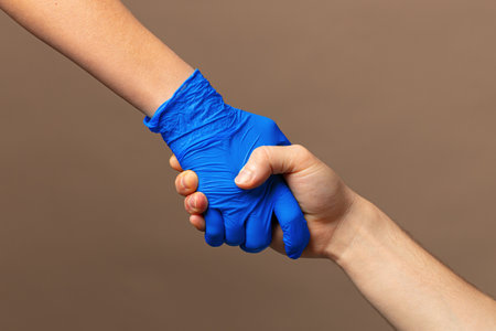 Handshake in a blue gloves, help concept. Personal hygiene during a pandemicの写真素材