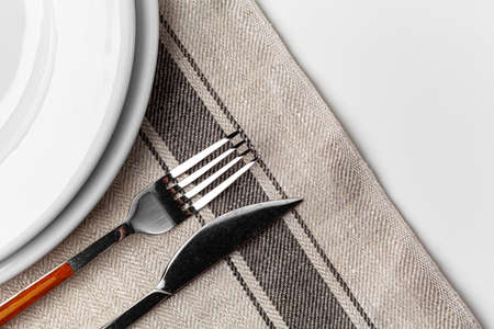 Fork, knife and plate on towel. Isolated on white background.