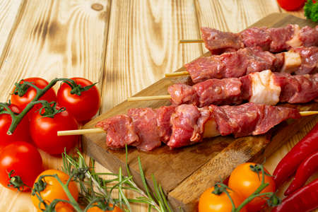 Raw kebab from meat on a wooden background with vegetables.の写真素材