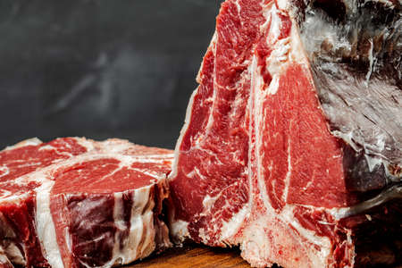 Raw T-bone steak cooking on stone dark table.の写真素材