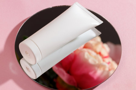 White tube of cream and mirror on pink backgroundの写真素材