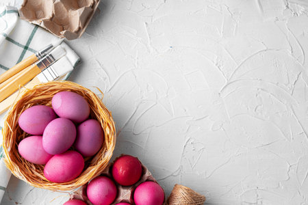 Painting Easter eggs in pink on white table, view from above