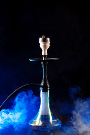 Smoking hookah on black background with color fogの写真素材