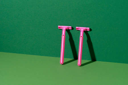 Disposable razor on green background, studio shot