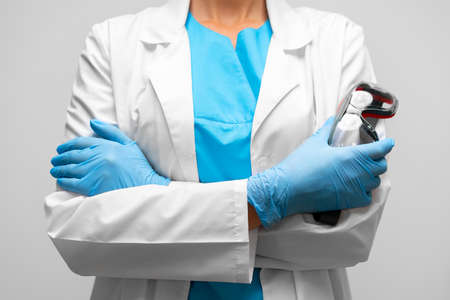 Unrecognizable woman doctor standing with crossed hands and holding protective glassesの写真素材