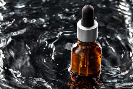 Photo of skincare serum bottle in black wavy waterの写真素材