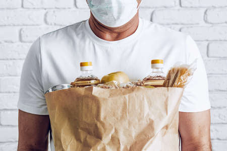 Delivery man in face mask and gloves. Food delivery, online shopping concept while coronavirus pandemiaの写真素材