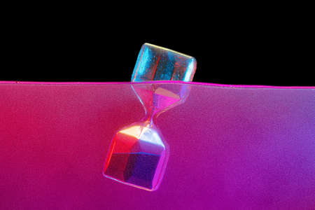 Hourglass in a pink liquid against black backgroundの写真素材