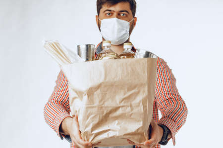 Man in a protective medical mask with a bag from a grocery storeの写真素材