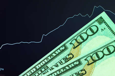 Dollars in front of a monitor with a price chart. Forex and trading.