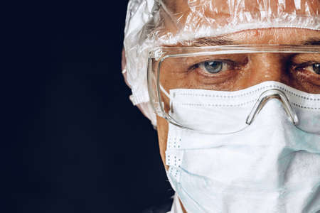 Male doctor wearing protective Mask and Goggles. Dark background.の写真素材