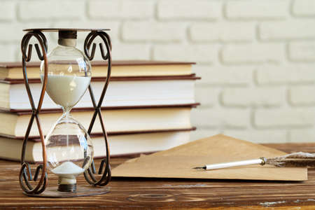Vintage hourglass against a stack of old booksの写真素材