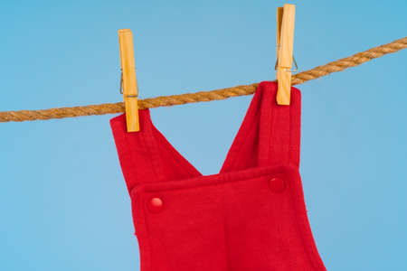Baby girl clothes pinned on a clothesline against blue backgroundの写真素材