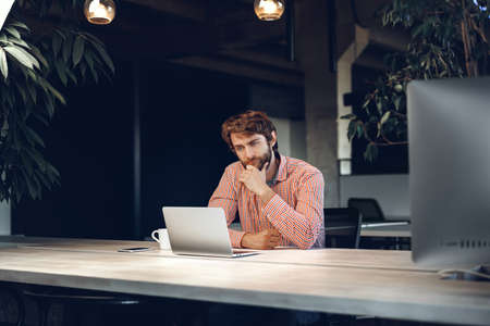 Puzzled thoughtful businessman sitting at his working table in an office