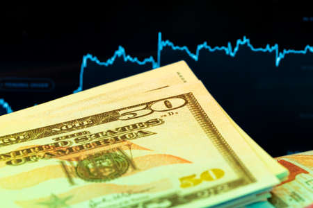 Dollars in front of a monitor with a price chart. Forex and trading.