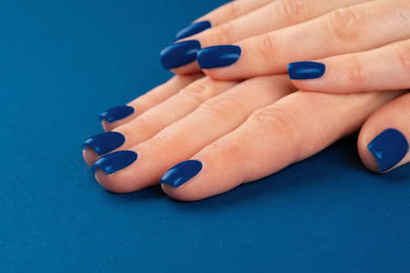 Female hands with manicure of classic blue color on blue background