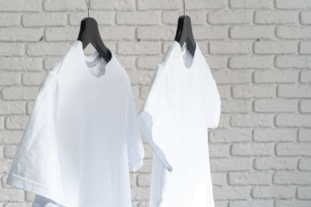 White t-shirt hanging on hanger against brick wallの写真素材