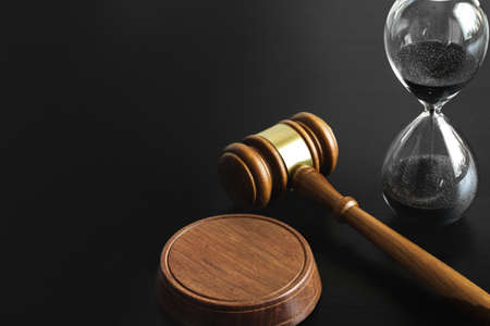 Court concept. Hourglass and judge gavel on table