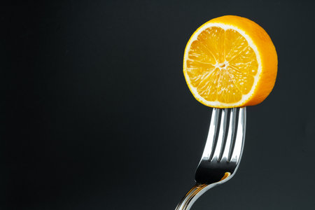 lemon on the fork on black background