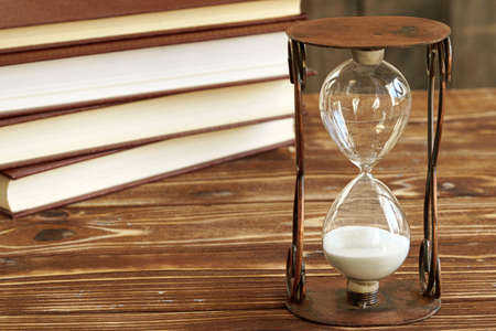 Vintage hourglass against a stack of old books
