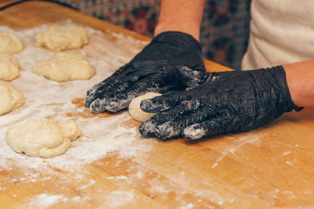 Chef hands in black gloves prepares dough close up