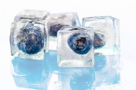 Frozen berries in ice cubes on pinkの写真素材
