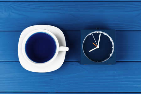 Top view of a cup of coffee on saucer on classic blue background