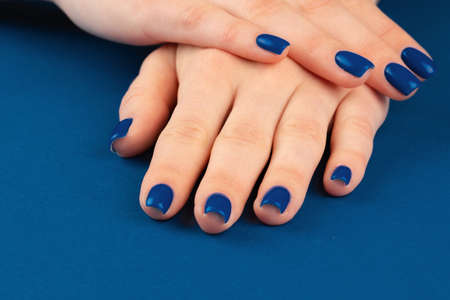 Female hands with manicure of classic blue color on blue background