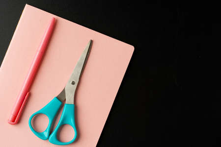 Notepad with pen and scissors on black table close upの写真素材