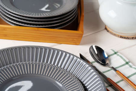 Glossy grey ceramic plate with cutlery on wooden table