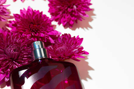 Perfume spray bottle and little flowers on gray background