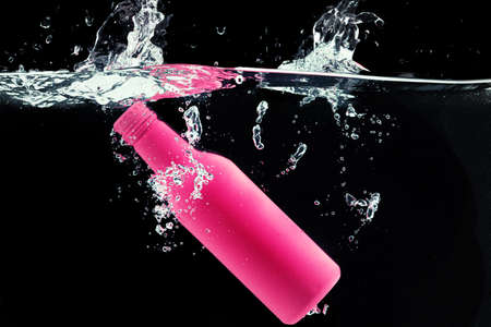 Painted bottle diving into the water with a splashの写真素材