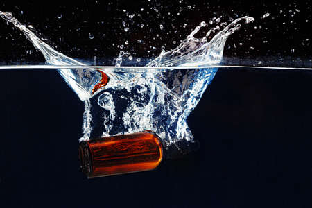 Bottle of cosmetic serum in clean transparent water in darkの写真素材