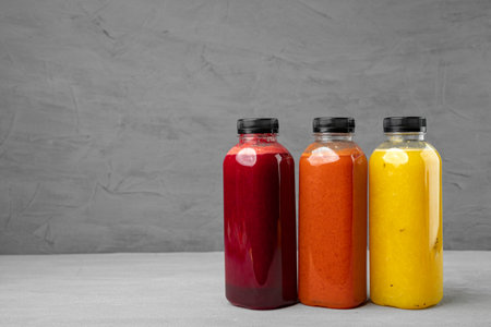 Three plastic bottles with freshly squeezed juice on gray backgroundの写真素材
