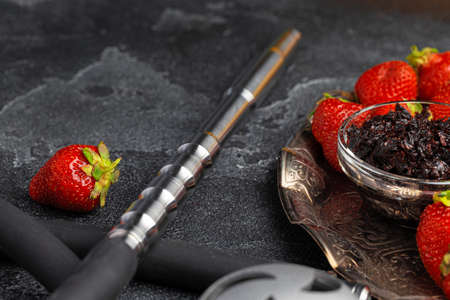 Hookah parts and strawberry on gray surface close up
