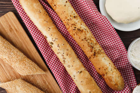 Baguette bread on brown wooden board close up