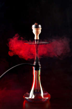 Smoking hookah on black background with color fogの写真素材